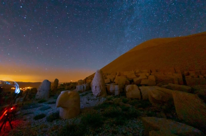 Ancient stone structures standing tall in a barren wilderness under a deep starry night sky, representing historical power and old testament foundations.