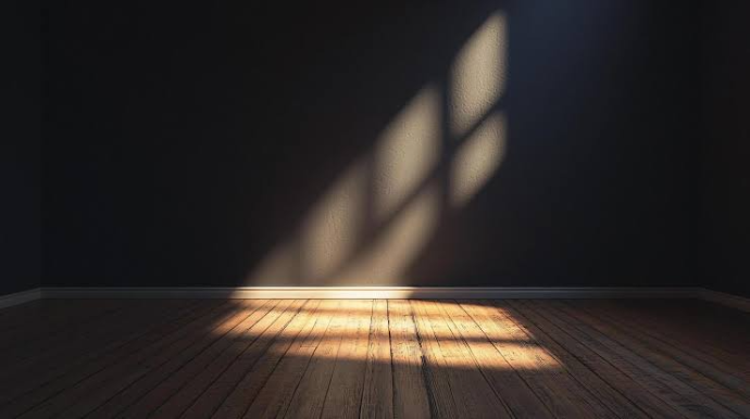 A solitary beam of bright sunlight cutting through a window and illuminating a modern, dark minimalist room with stark stone walls.