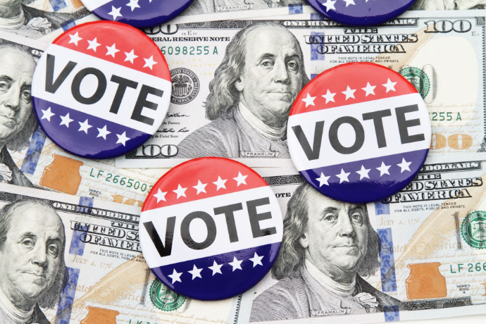 Campaign buttons resting on US hundred dollar bills representing political financing and election money